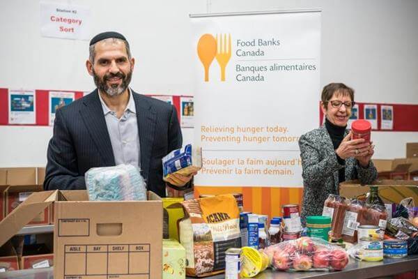 Man & woman holding food at a food drive.