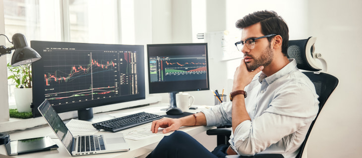 Man looking at advanced charts trading monitors