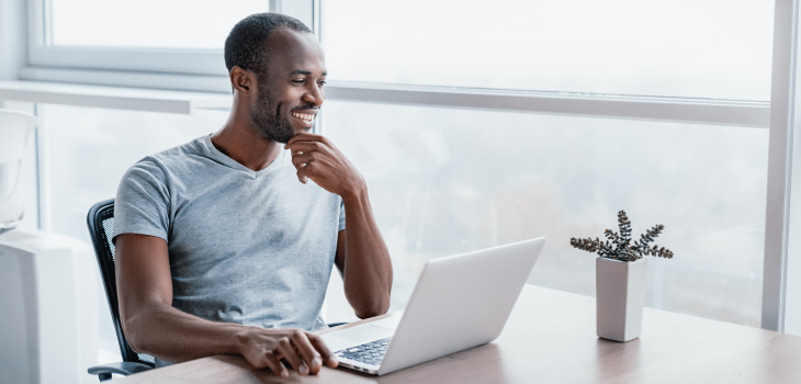 Man smiling at laptop sunshine