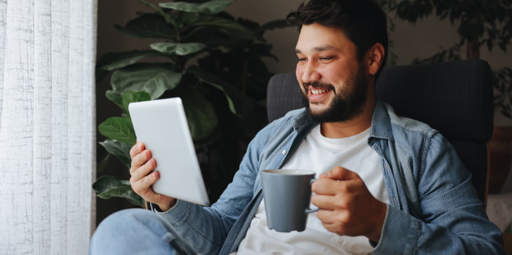 Bearded man with coffee and tablet