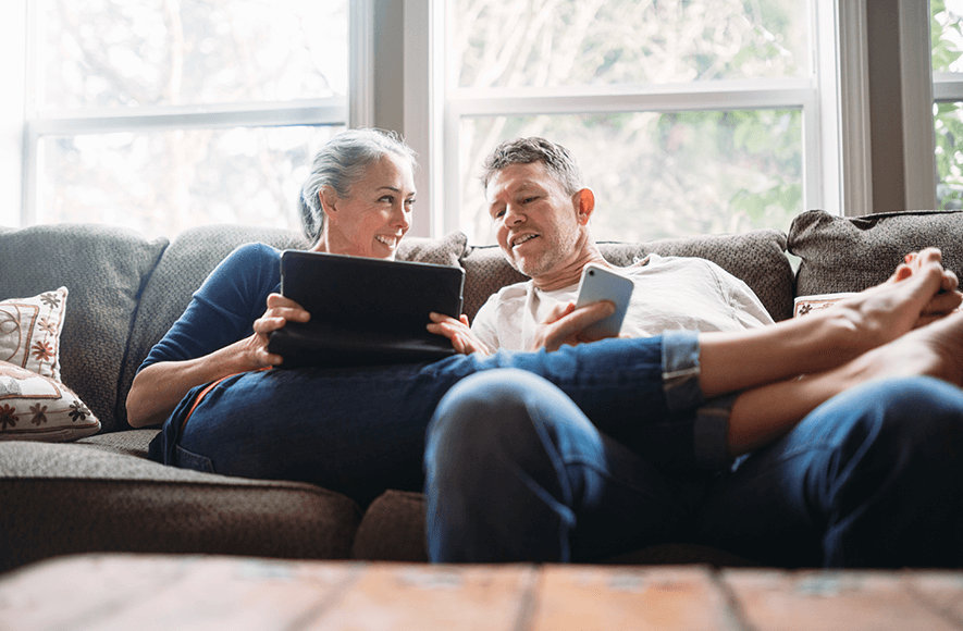 Mature couple relaxing with tablet and phone