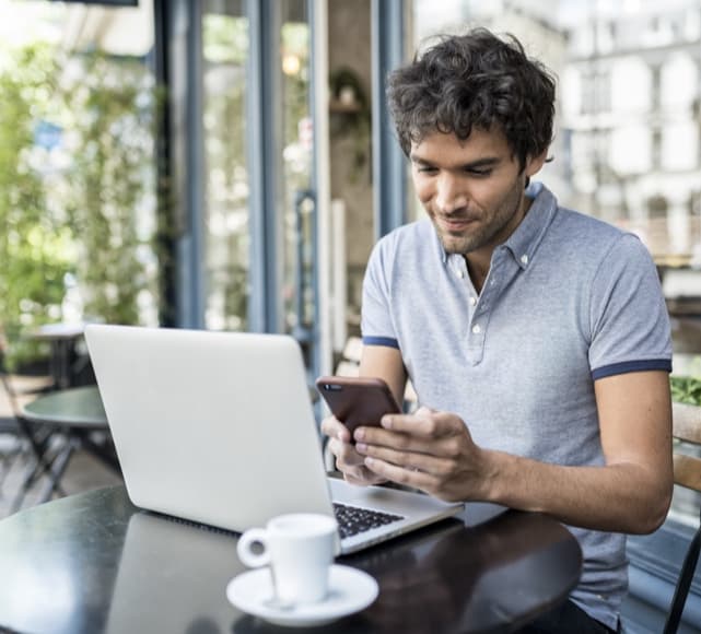 Man with laptop and phone smiling